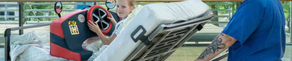 Schwester Katrin schiebt die junge Patientin Greta in ihrem Rollbett über den Krankenhausflur im Uniklinkum Dresden. Foto: Michael Kretzschmar für das UKD