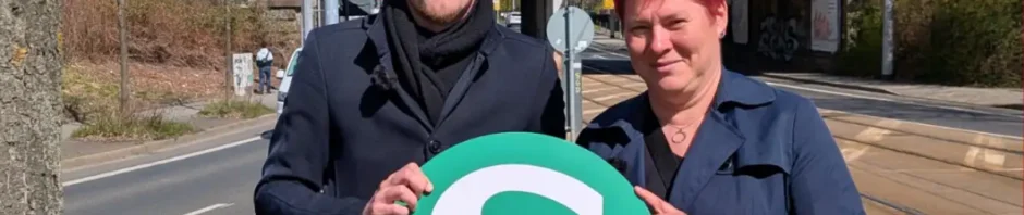 Stefan Engel und Dana Frohwieser werben mit einem S-Bahn-Schild für ihren Plan, an der Kreuzung von Teplitzer Straße und Bahnstrecke einen neuen Halt einzurichten. Foto: SPD-Fraktion Dresden